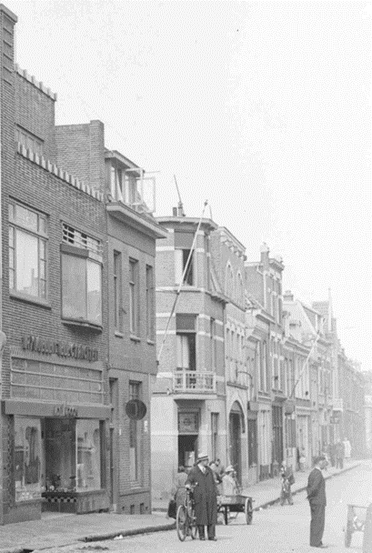 Het winkelpand van de inleggerij en azijnfabriek van de familie Roghmans, sinds 1859 op dit adres gevestigd. Daarnaast de rund-, kalfs- en varkensslagerijslagerij van de firma Rosendaal-Wouters die zich in 1938 in de straat vestigde, dan de ingang van Uijen, hoefsmid en op 67 de firma "De Kroon" in rijwielen en electrische apparaten. Bij het bombardement van 22 februari 1944 werd de straat weggevaagd, 1938-1944 (detail van GN11020, RAN)