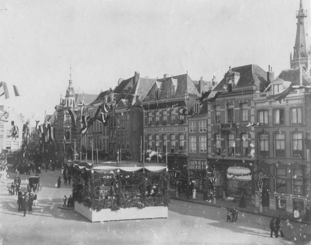 Links het torentje van warenhuis Bahlmann: Links het torentje van het Warenhuis "Bahlmann"; Het gedeelte tussen de Broerstraat en de Augustijnenstraat, gezien in de richting van de Burchtstraat; de feestversiering is aangebracht ten gunste van de troonbestijging door koningin Wilhelmina; rechts boven de toren van de St. Dominicuskerk in de Broerstraat, , 9/1898 (RAN) Semmelink