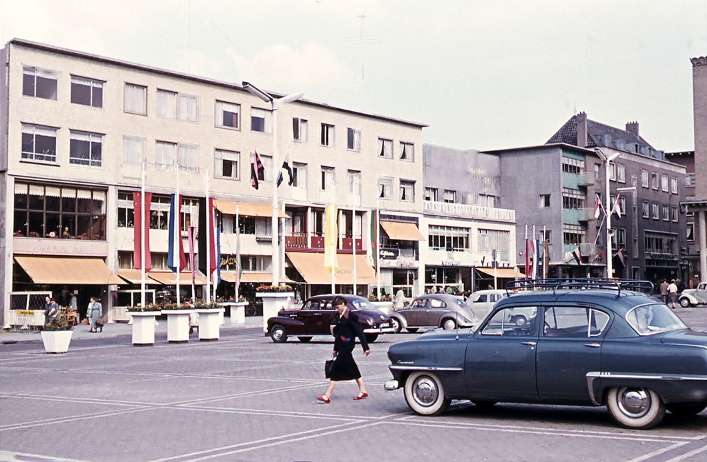 De noordwand van het plein met de winkelpanden van (v.l.n.r.) Lunchroom annex Banketbakkerij Pleinzicht (van W.P.H.A. Cornelissen, Plein 1944 nr. 135), Sigarenmagazijn H.W.R. Brans (nr. 136), Juwelier en Horloger A.J. Janssen (nr. 137), P. Jacobs Textiel en Tricotage (nr. 140), Cafetaria Centrum Expresse (van Albert en Piet Cloosterman, nr. 141), A.J. Holland Schoenenmagazijn (nr. 143), Foto A.M. Verweij (nr. 145) en Parfumerie en Bijouterie J.E. Albers (nr. 146) ; geheel rechts Boekhandel Kloosterman (op de hoek met de Broerstraat), 1954 (Jeroen van Lith via RAN)