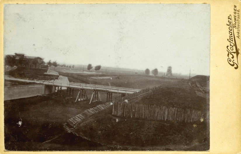 De tweede houten brug buiten de Molenpoort over de droge gracht ter hoogte van het huidige Keizer Karelplein, met links het Station van de spoorlijn Nijmegen-Kleef, de 'Kleefschebaan' (op de plek van het huidige Concertgebouw de Vereeniging), 1875 (Gerard Korfmacher, RAN F23031)