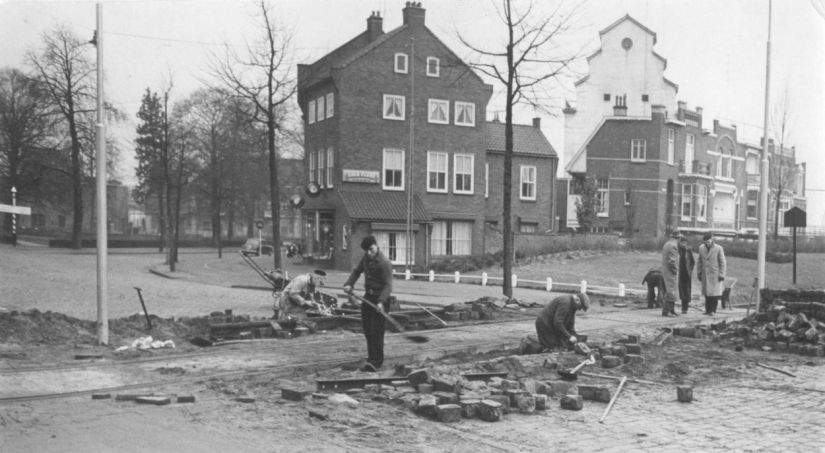 Reconstructiewerkzaamheden, gezien in de richting van het Krayenhoffpark (links). Links van het midden het begin van de Weurtseweg. Rechts panden aan de Waalbandijk. Op de achtergrond de witte graansilo van de Handel in bakkerijgrondstoffen Van Lith en Zonen (Weurtseweg 32), 5/12/1959 (Fotopersbureau Gelderland via F20030 RAN CCBYSA Auteursrechthouder J.F.M. Trum)