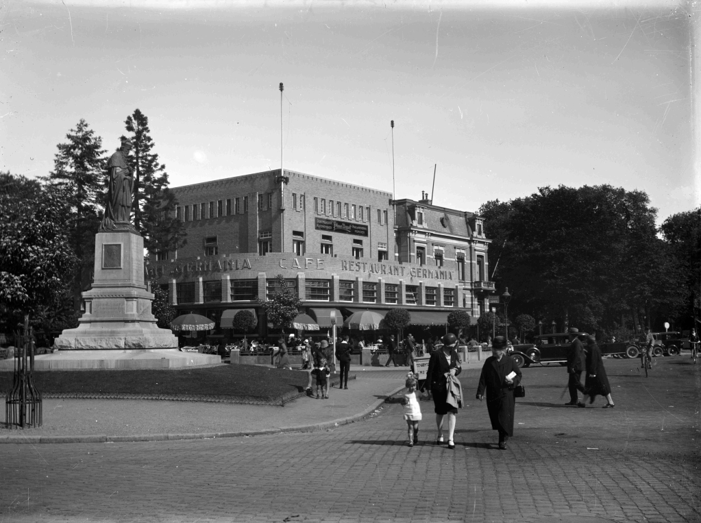 Café-Restaurant Germania met op de voorgrond links het standbeeld van Bisschop Hamer, 1928-1930 (GN16342)