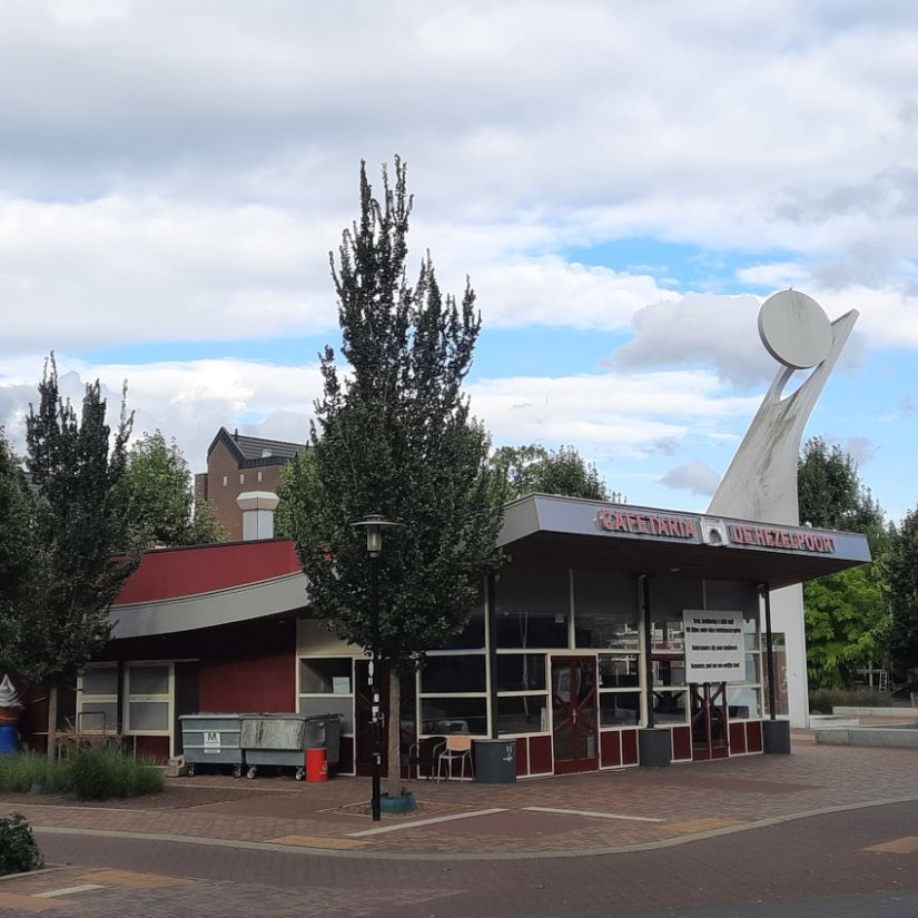 Joris Ivensplein met op voorgrond eethuis/café en op achtergrond Joris Ivens monument, september 2023