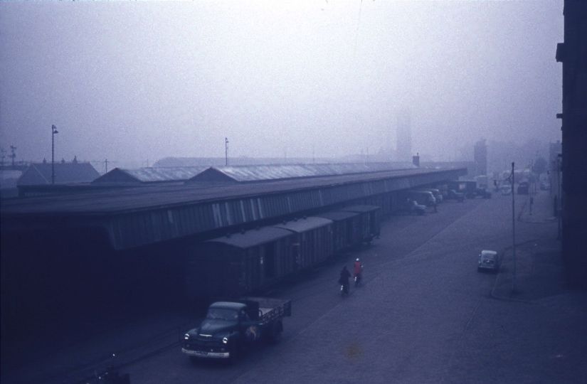 Loodsen van het aan de spoorwegen gelieerde expeditiebedrijf Van Gend & Loos. In de verte het ruiterstandbeeld en het station, 1957 (Jeroen van Lith via D1062 RAN CC0 tevens Auteursrechthouder)