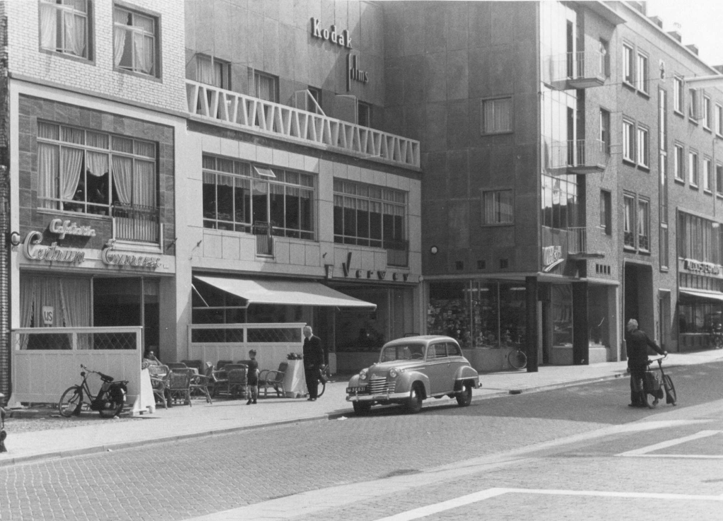 De panden van Cafétaria Centrum Expresse; de Schoenhandel Holland; Fotohandel Verwey; de Parfumeriezaak Albers, en een gedeelte van Boekhandel Kloosterman, 1952 (Commissariaat van Politie, Afd. Fotografie via F31792 RAN)