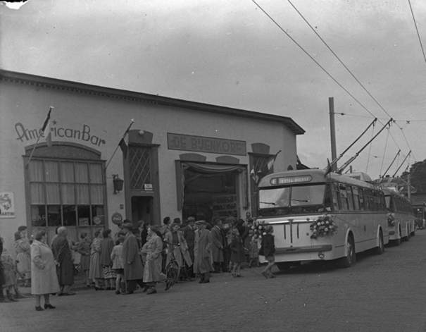 Tijdelijke vestiging van de Bijenkorf op Hertogstraat 8, detail van foto Doortrekking van de trolleybusbaan; links de American Bar (Wintersoord ) en daarnaast De Bijenkorf (Hertogstraat 8), september 1952 (Gelderse Fotohandel Nijmegen via GN17098 RAN, Auteursrechthouder J.F.M.Trum CC-BY-SA)