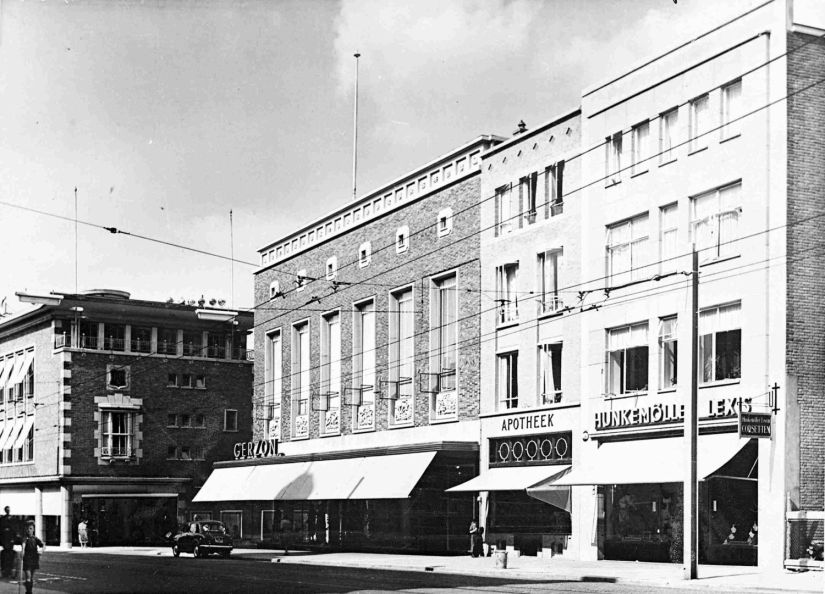 Panden gelegen tegenover het Stadhuis in de Burchtstraat, van rechts naar links; Hunkemöller Lexis, de Apotheek Bijleveld en Modezaak Gerzon en geheel links Peek & Cloppenburg , gezien in de richting van de Grote Markt, 1955-1956 (GN3711 RAN)
