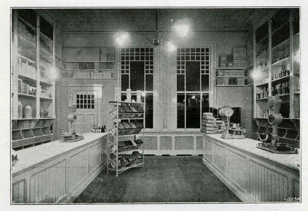 	Verlichte toonbanken in de Winkelvereniging "Eigen Hulp" bij avond, met behulp van zijwaarts aangebrachte wandarmen (Installatie Alewijnse & Co.). Reproductie uit: Gebruikt Electriciteit! Reclame uitgave der Gemeente-Electriciteitswerken te Nijmegen, eerste serie no. 3 'Onze Winkels', Nijmegen, 1910 (P.H. Kouw via F47590 RAN)