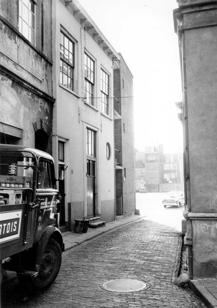 De nauwe ingang van de Sint Anthoniusplaats met een vrachtwagen van drankengroothandel van Teeseling, die daar opslagplaats had in de kelders waar in 1967 de discotheek Jo's Kelders het levenslicht zag; op de achtergrond de Eiermarkt , 1958-1967 (Gemeentepolitie Nijmegen via F18563 RAN CC0)