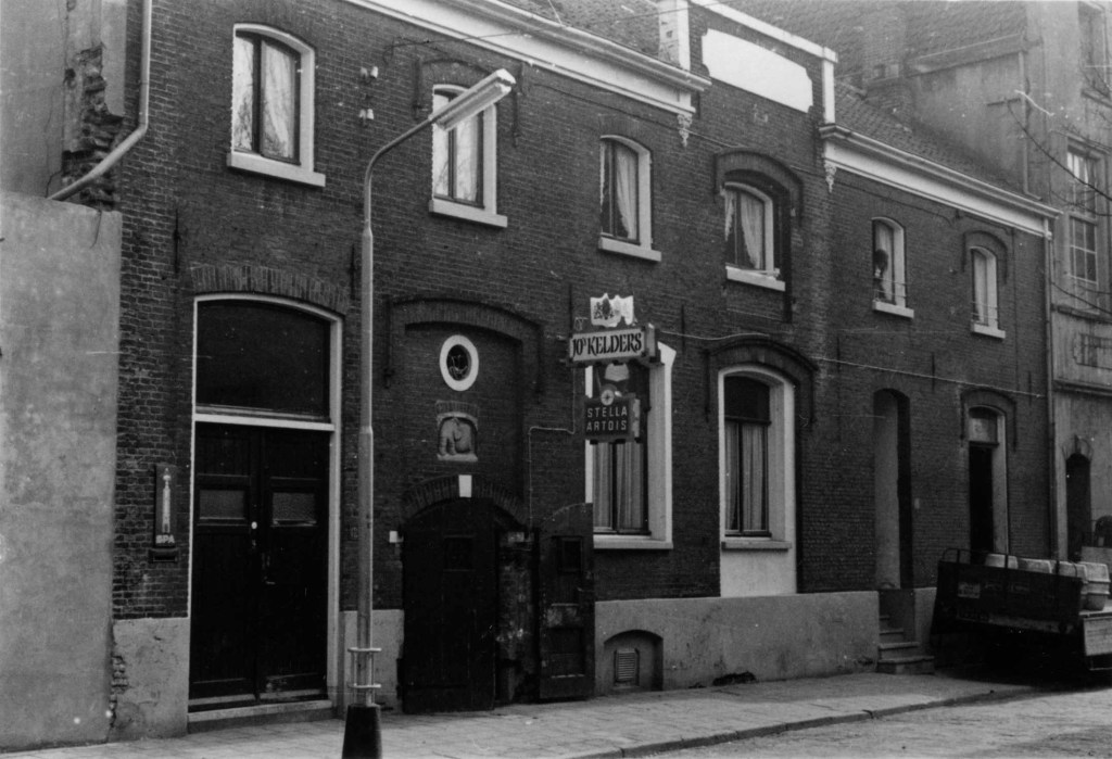 St. Anthoniusplaats 12-13 in 1971: woonhuizen en Bar Dancing Jo's Kelders ; boven de ingang het relief "Man, die een ton rolt ", gemaakt in 1951 door Ed van Teeseling i.o.v. wijnhandelaar Elias Broekkamp, 1971 (Prof. dr. E.F. van der Grinten via F26237 RAN CCBYSA)