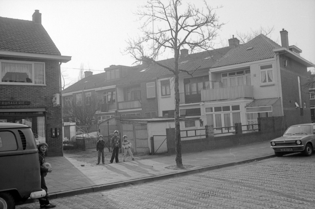 Kijkend vanuit de Sperwerstraat naar de achtergevel van het hoekpand op de Krayenhofflaan 265; Links is de Kaaswinkel - Fromagerie aan de Sperwerstraat 35 te zien, 1978-1980 (Gemeente Nijmegen via KN11413-18 RAN CC0)