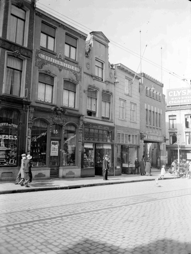 Het bovenste gedeelte van de zuidwand van de Lange Hezelstraat , met o.a. Slijterij T.G. van de Hof , G. van Leeuwen een slagerij en De Gelderlander, Lange Hezelstraat 15, 17, 19 en 21, 1920 (GN4871 RAN)