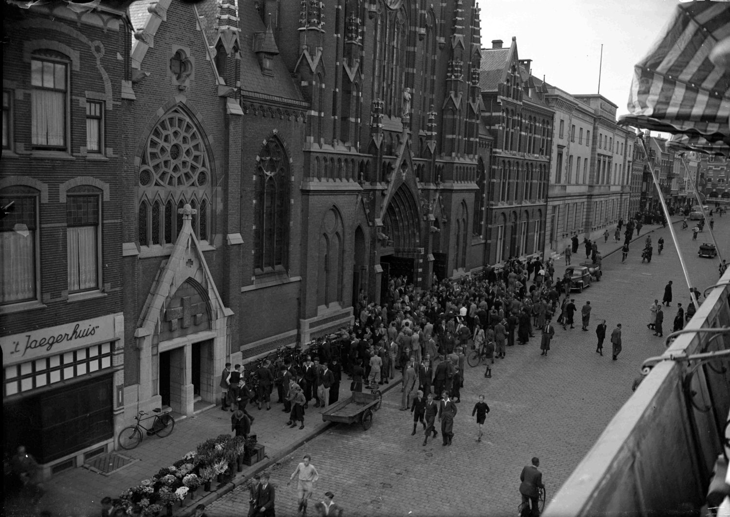 De Molenstraat , gezien in zuidelijke richting , met links 't Jaegerhuis Damesmode en daarnaast de (oude) Petrus Canisiuskerk , de pastorie en het Oud Burger Gasthuis, 1934-1944 -afgaande op de verbouwing is de foto van na 1940 (GN5431 RAN)
