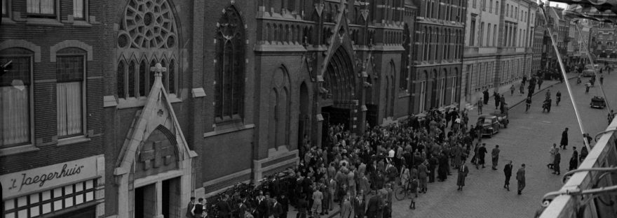De Molenstraat , gezien in zuidelijke richting , met links 't Jaegerhuis Damesmode en daarnaast de (oude) Petrus Canisiuskerk , de pastorie en het Oud Burger Gasthuis, 1934-1944 -afgaande op de verbouwing is de foto van na 1940 (GN5431 RAN)
