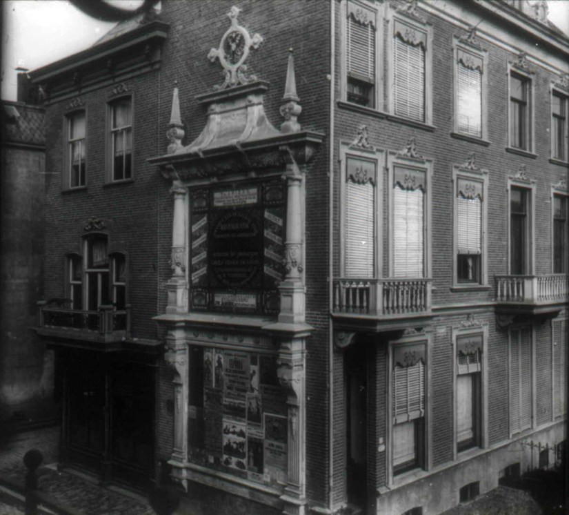 Een reclamevlakte in omlijsting in renaissancestijl naast Café De Burchtpoort om een raamloze zijgevel te camoufleren. Met beeldhouwerswerk van De Leeuw Sr. en Jr. op de plaats waar eens de 14e eeuwse en in 1826 afgebroken Burchtpoort stond. Het aanplakbord werd in 1887 naar een ontwerp van gemeente-architect Ir. Jan Jacob Weve aangebracht, 1887 (collectie dr. Jan Brinkhoff via D89 RAN CC0 tevens Auteursrechthouder)