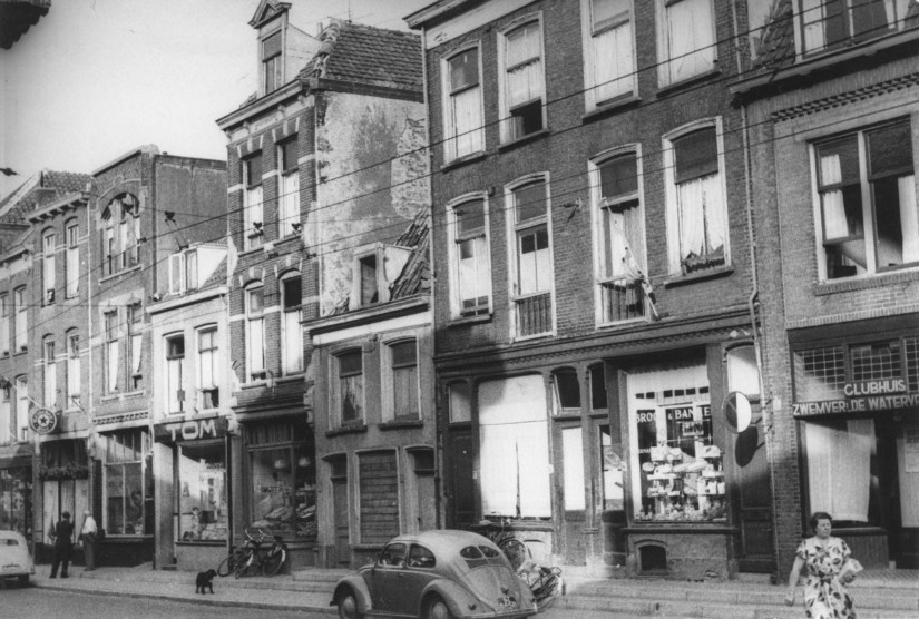 De oostzijde van de Bloemerstraat met o.a. v.l.n.r. Café W. Smolders (Bloemerstraat 34) , Thom's Verfhandel (van Th. A. van Cleef) (Bloemerstraat 28A), de winkel in groente en fruit van P. Holleman (Bloemerstraat 26) en (tweede van rechts) Brood- en Banketbakkerij J. Eickmans (Bloemerstraat 14), 1954-1955 (F12830 RAN)