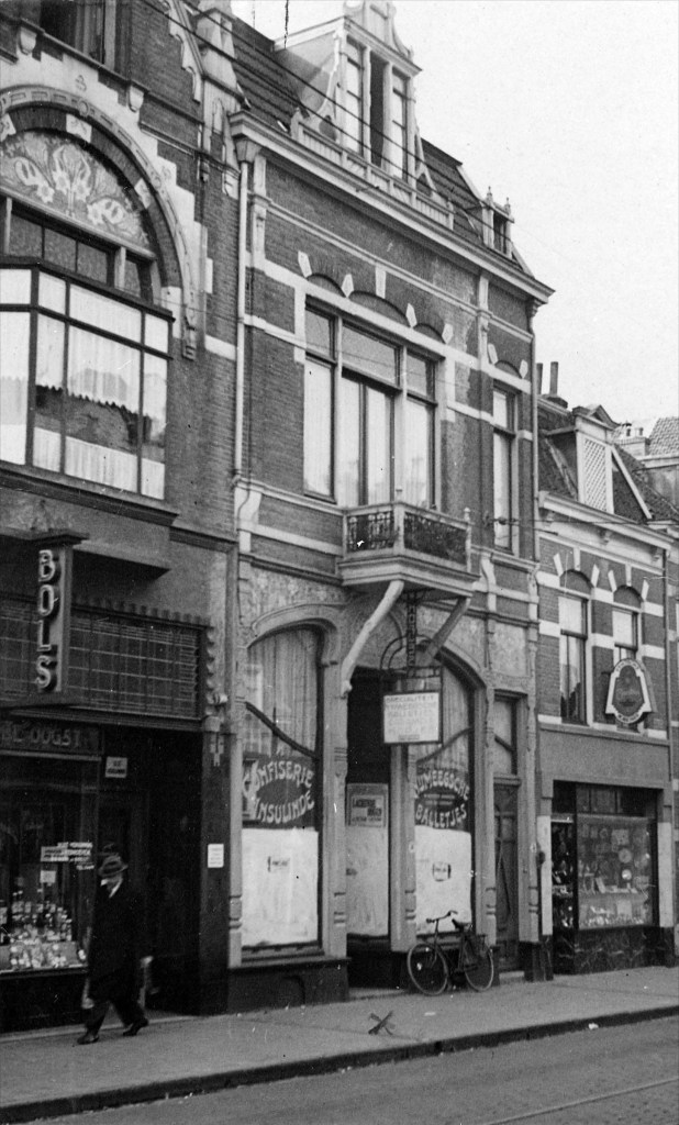 Straatbeeld, eind jaren dertig, met, van links naar rechts, wijnhandel en slijterij 'De Oogst' van J. Verhoeven, confiserie 'Insulinde' van H.W.H. van Boldrik en de winkel van horlogemaker en goud- en zilverhandelaar F.P.M. Tromp, St. Jorisstraat 12-14a-16, 4/1939 (ZN35624 RAN)