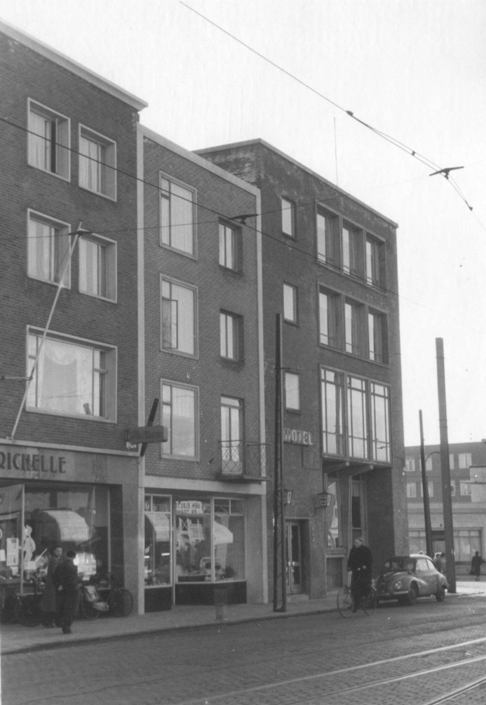 Links de Kantoorboekhandel van G.C. Richelle (Kelfkensbos 22, geopend op 18 juni 1953), daarnaast de slagerij Fa. Joh. van Swelm van L.M.A. van Swelm (Kelfkensbos 21, geopend op 15 juli 1953) en rechts Hotel Cafe Restaurant De Roemer van H.P. Selbach (Kelfkensbos 19-20, hoek Hertogstraat. geopend op 27 januari 1955), 1955 (Commissariaat van Politie, afd. Fotografie via F17676 RAN CC0)