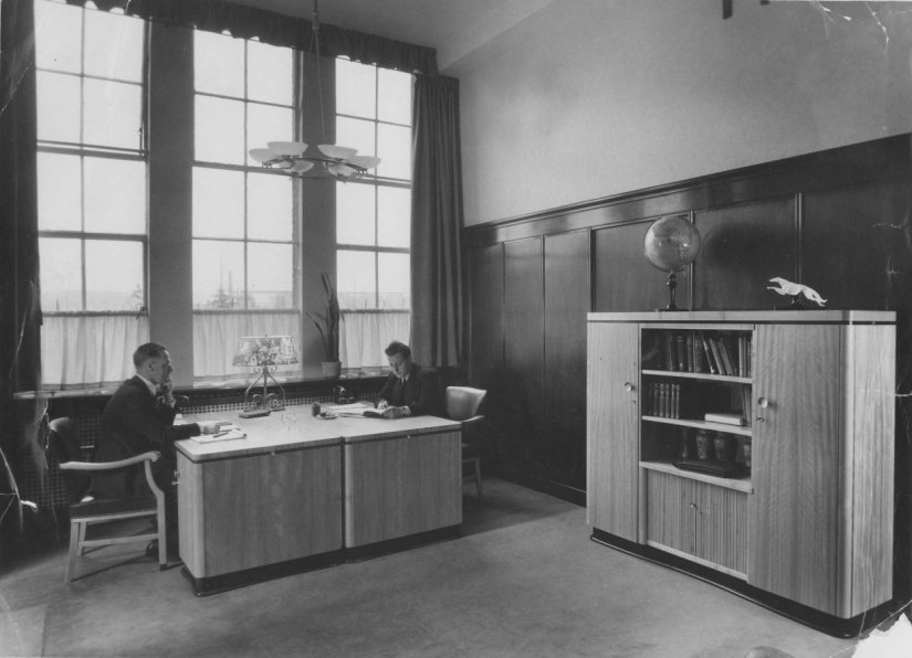 Directiekamer van de Schoenfabriek van Swift. Links Ferdinand Biessels, rechts Herman Otten, op de kast het logo van Swift, een Barsoi oftewel Russische windhond, Muntweg, 1946-1950 (F58956 RAN)