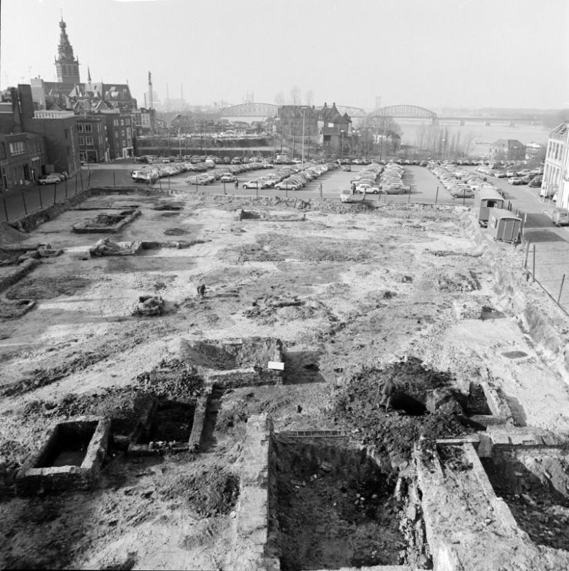 Bij opgravingen door het ROB kwamen 2 parallelle grachten uit de laat Romeinse tijd aan het licht, de buitenste verdedigingswerken van de 4e eeuwse versterking op het Valkhof. In de linker bovenhoek en rechts onder zijn resten van laat-middeleeuwse huizen te zien, Eiermarkt, 13/2/1981 (Ber van Haren via ZN34506 - B RAN CC0 Auteursrechthouder: Gemeente Nijmegen)