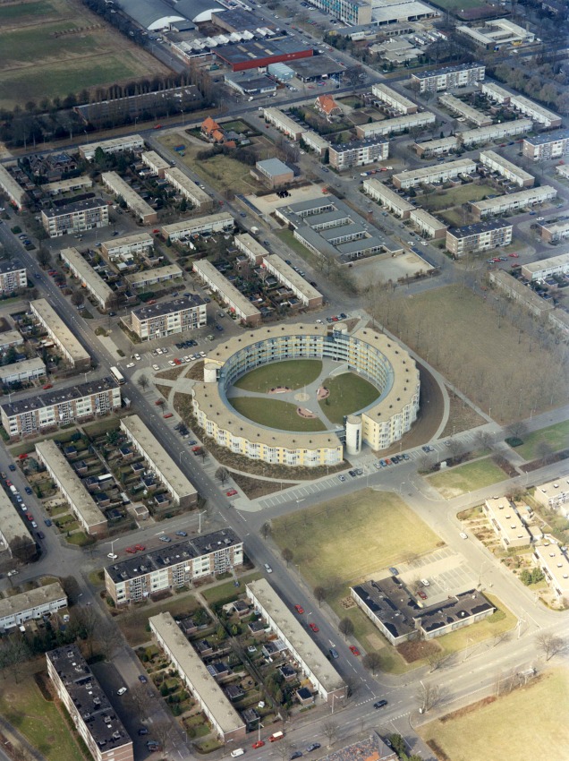 Obliek luchtfoto van een deel van de wijk Grootstal met het cirkelvormige appartementencomplex 'De Ring', het werd in 1993 gebouwd naar een ontwerp van architect Theo Bosch. Voorheen stond hier de Verrijzenis van Christuskerk, 4/1996 (Ger Loeffen via F38331 RAN CCBYSA)