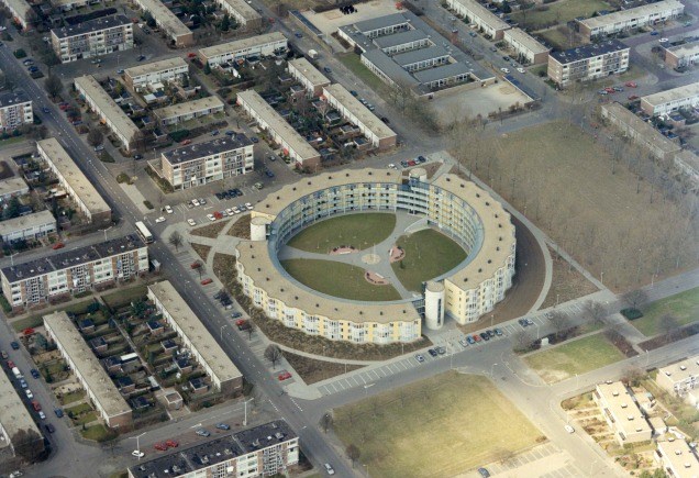 Obliek luchtfoto van een deel van de wijk Grootstal met het cirkelvormige appartementencomplex 'De Ring', het werd in 1993 gebouwd naar een ontwerp van architect Theo Bosch. Voorheen stond hier de Verrijzenis van Christuskerk, 4/1996 (Ger Loeffen via F38331 RAN CCBYSA)