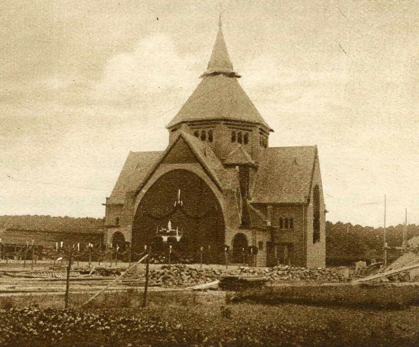 Een versierde Onze Lieve Vrouw van Lourdeskerk kort na de inwijding. De kerk werd ontworpen door ir. H. Thunissen uit 's-Gravenhage ; Van de kerk staat hier alleen nog maar de koepel en het achterste gedeelte , met een voorlopige voorgevel. Het schip en de huidige voorgevel zouden pas in 1948 gerealiseerd worden ; de twee beoogde torens zullen nooit worden gebouwd, Hatertseweg 113 St. Anna, 29/6/1925 (F9536 RAN)