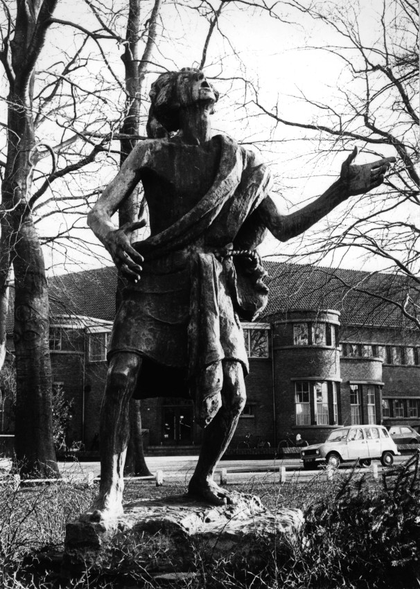 Een beeld van brons, voorstellende de H. Stephanus, staande in het plantsoen voor de St. Stephanuskerk, vervaardigd door Albert Termote in 1951. Rechts het schoolgebouw van Mater Dei (uit 1930), Berg en Dalseweg, 1975 (Frans Kup via F12613 RAN CCBYSA)