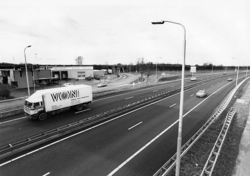De A52 door Lent, met de afslag naar de Griftdijk Noord. Op deze plek moet in de toekomst het grote NS-station en het Van der Valk Hotel komen. Kuipers Plantenexport en Groothandel B.V. moest hier voor plaats maken. De foto is gemaakt vanaf de Lentse Lus, 14/12/1993 (Ger Loeffen via F95245 RAN CCBYSA)