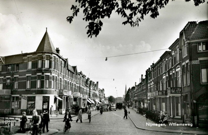 Straatbeeld Willemsweg, gezien vanaf de oprit naar de Graafseweg, in de richting van de Groenestraat. Links, het begin van de Tollensstraat met op de hoek 'Kulo's Muziekhandel', 1949-1951 (J. Sleding via F91481 RAN)