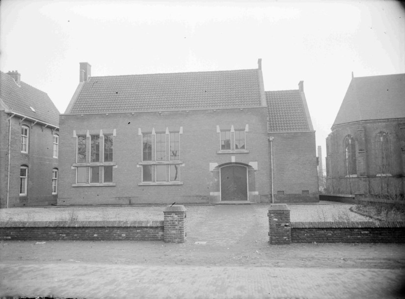 De rk lagere Tuinbouwschool (een initiatief van de Noord-Brabantse Christelijke Boerenbond), die op 18 maart 1933 werd geopend in de door de gemeente beschikbaar gestelde voormalige openbare school gebouwd in 1892, samen met de naastliggende onderwijzerswoning, gelegen aan wat toen de Dorpsstraat heette. In 1955 werd de school grondig verbouwd. Rechts een gedeelte van de Petruskerk. Door een bominslag op 22 juli 1942 werd een groot gedeelte van de school verwoest, Schependomlaan 81, 1953 (GN9636 RAN)