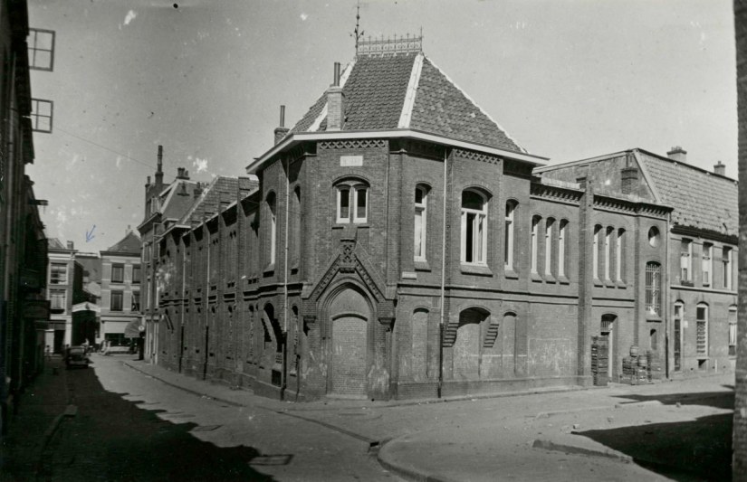 De voormalige bank van lening op de hoek Hessenberg (rechts) en Pijkestraat (links), een fraai voorbeeld van de neo baksteen gotiek, één van de weinige overgebleven openbare gebouwen van de stadsarchitect J.J. Weve gebouwd 1889-1890, augustus 1947 (F93728 RAN)
